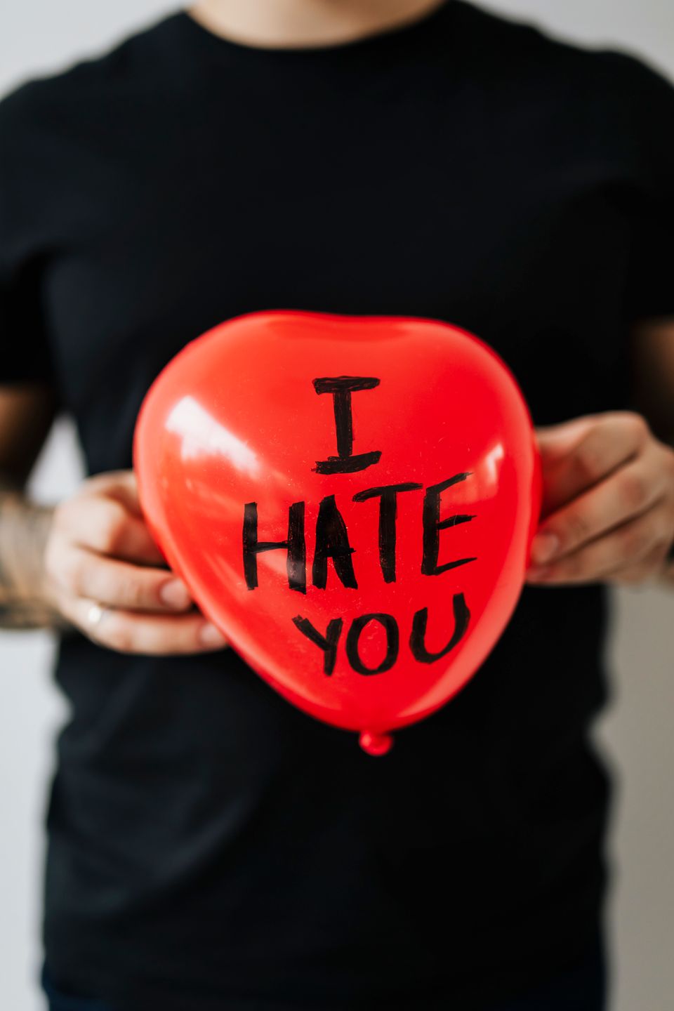 Mand holder en hjerteformet rød ballon, hvor der står "jeg hader dig" på. 