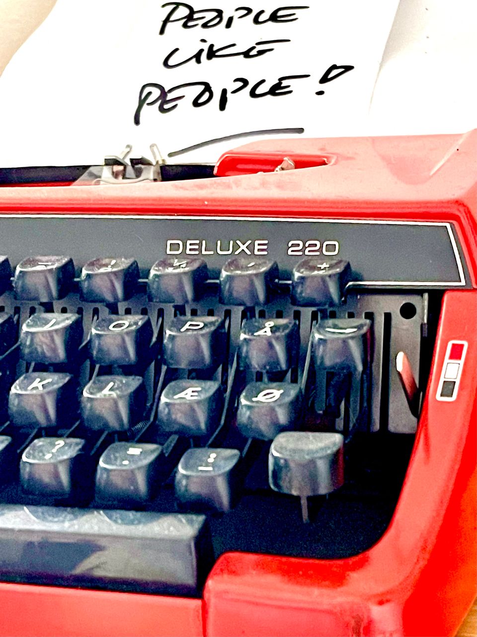 Rød skrivemaskine med seddel med ordene: People like people