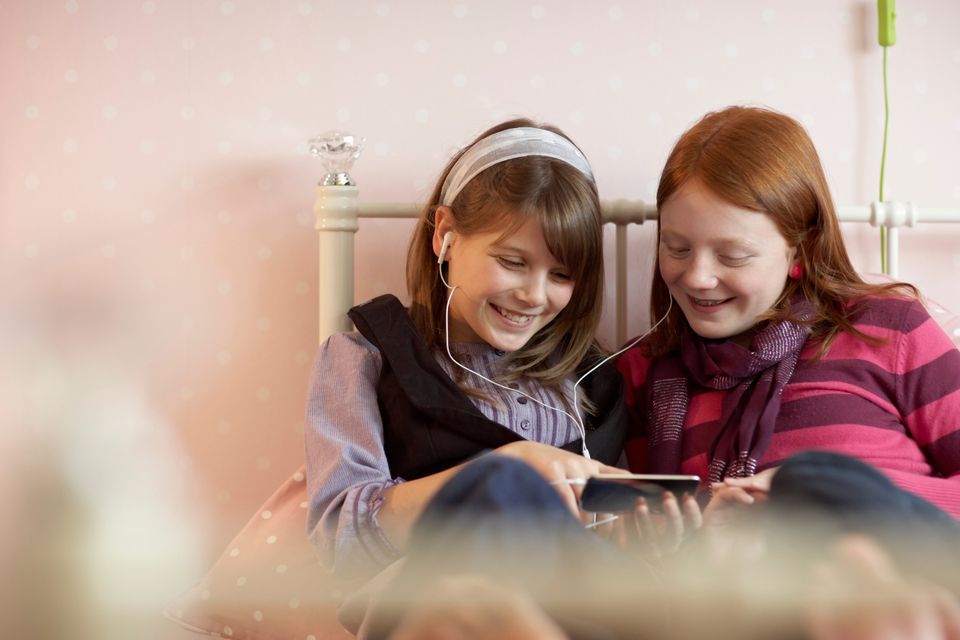 To piger ser på samme skærm og deler hovedtelefoner