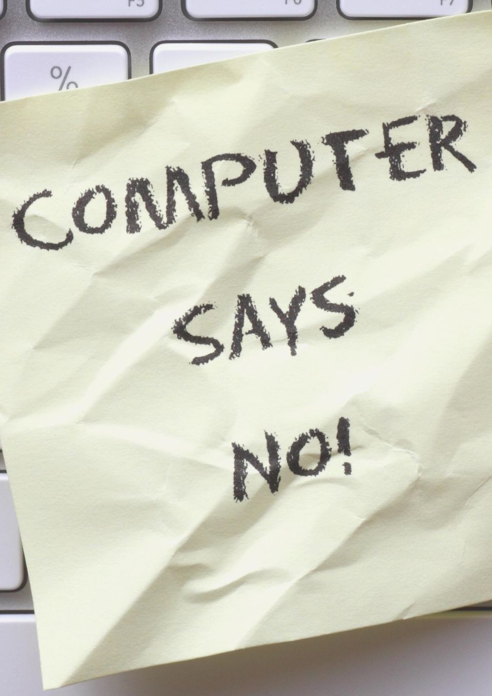 Gul seddel med teksten "Computer says no" liggende på tastatur