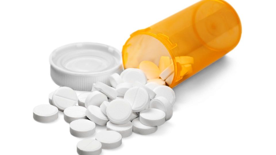Et amerikansk pilleglas med hvide piller på hvid baggrund